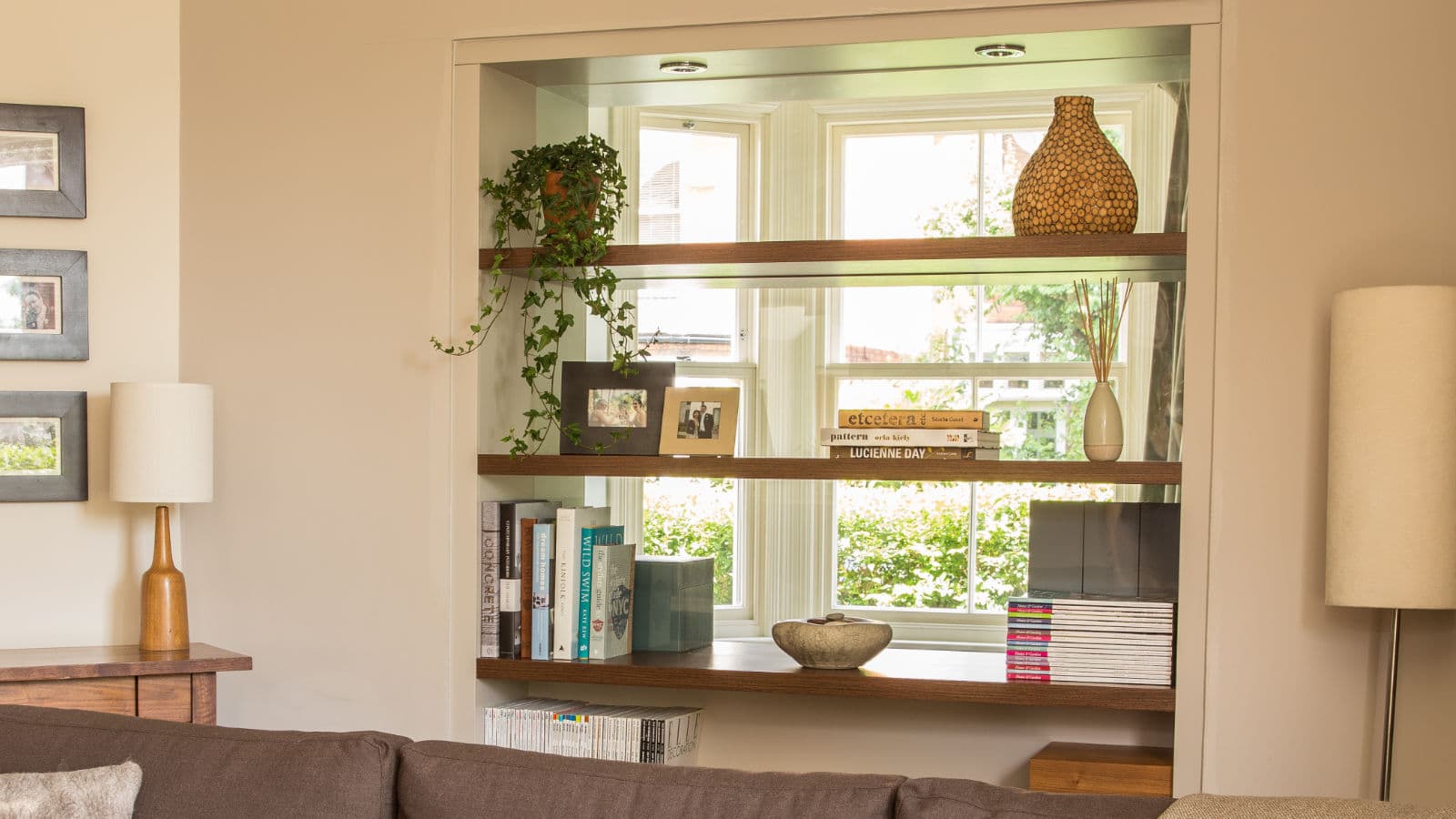 Double-sided glazed bookcase set into the wall between living room and study in Caroline Bolt's own home, allowing natural light to pass through both rooms