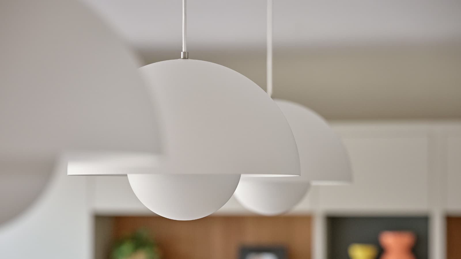 Three white pendant lights hanging in an open plan dining space.